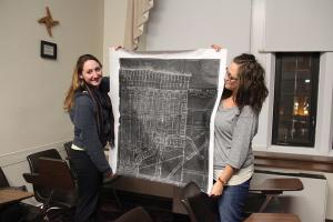 Taylor Rollins photo: Public history majors Allie Stacy and KayAnn Warner hold a 1922 map of the Frontier Park area in the city of Erie for the “Erie Places, Erie Stories” project.